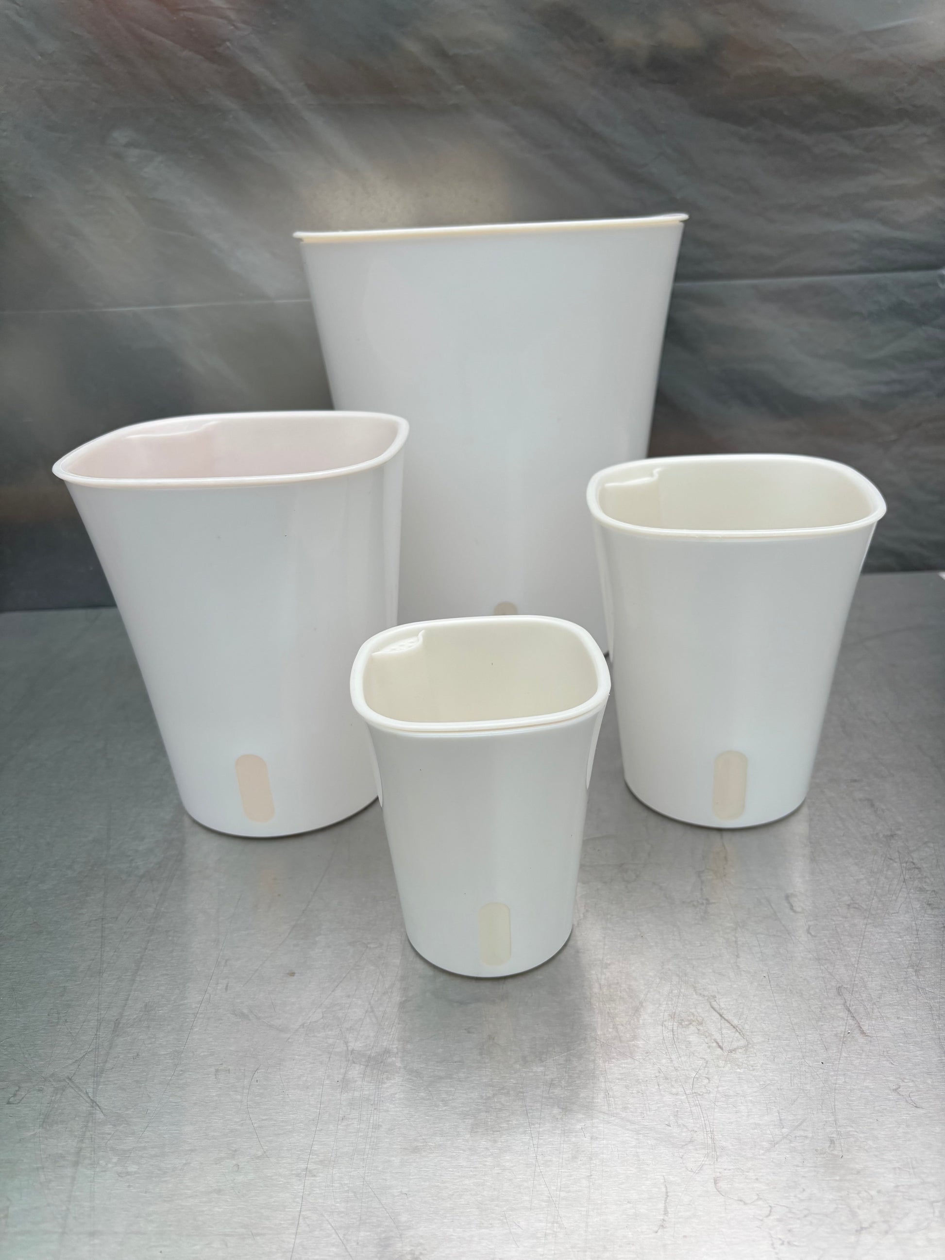 Set of four white self-watering planters in various sizes with water level indicators, ideal for indoor gardening and low-maintenance plant care.
