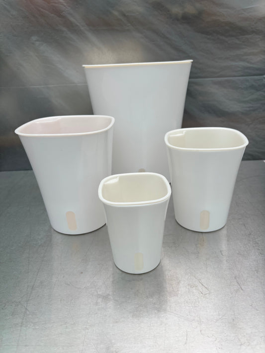 Set of four white self-watering planters in various sizes with water level indicators, ideal for indoor gardening and low-maintenance plant care.