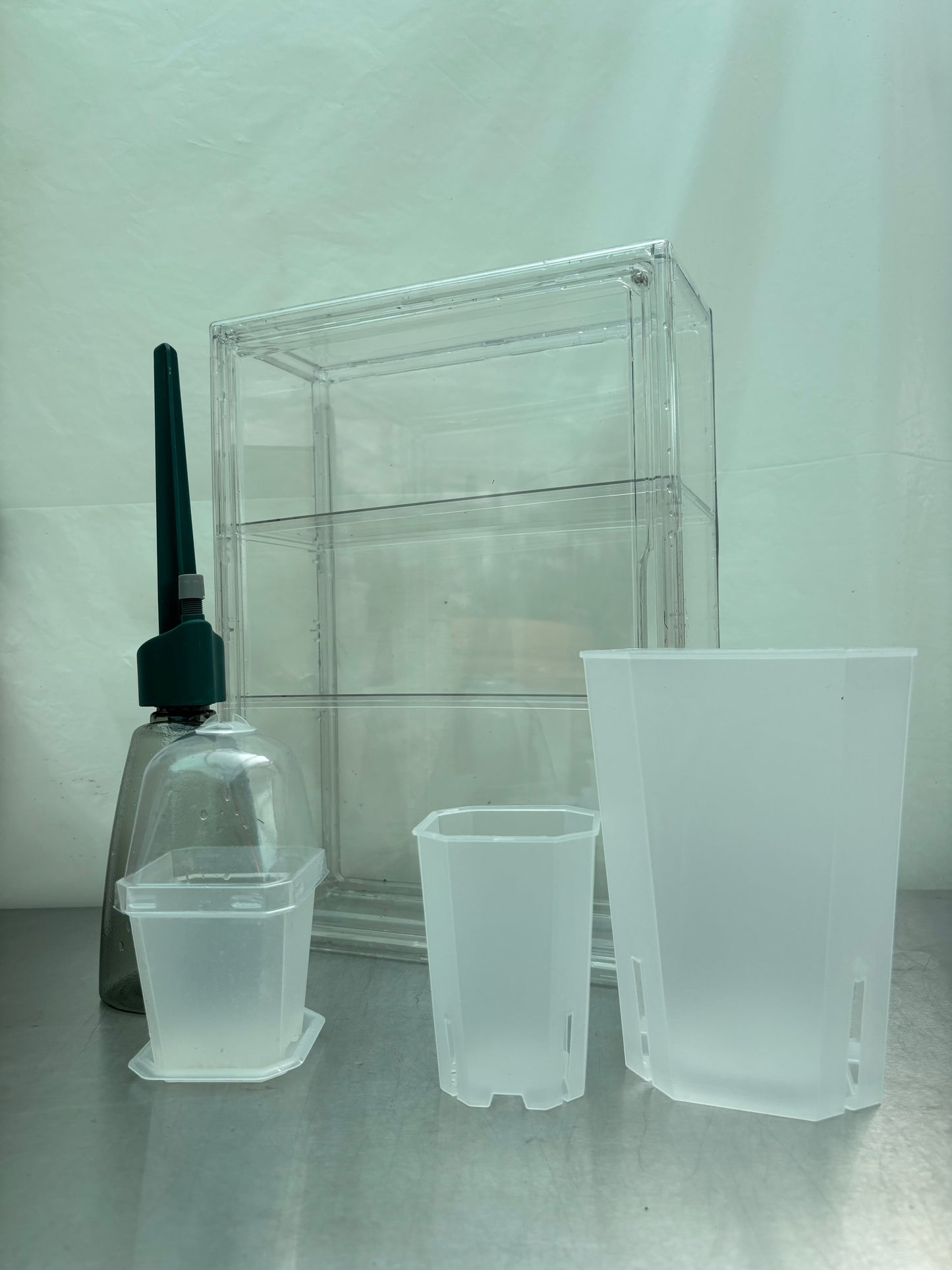 Complete Greenhouse Pro Bundle featuring transparent grow box, watering tool, and various translucent pots for serious plant propagation setups.