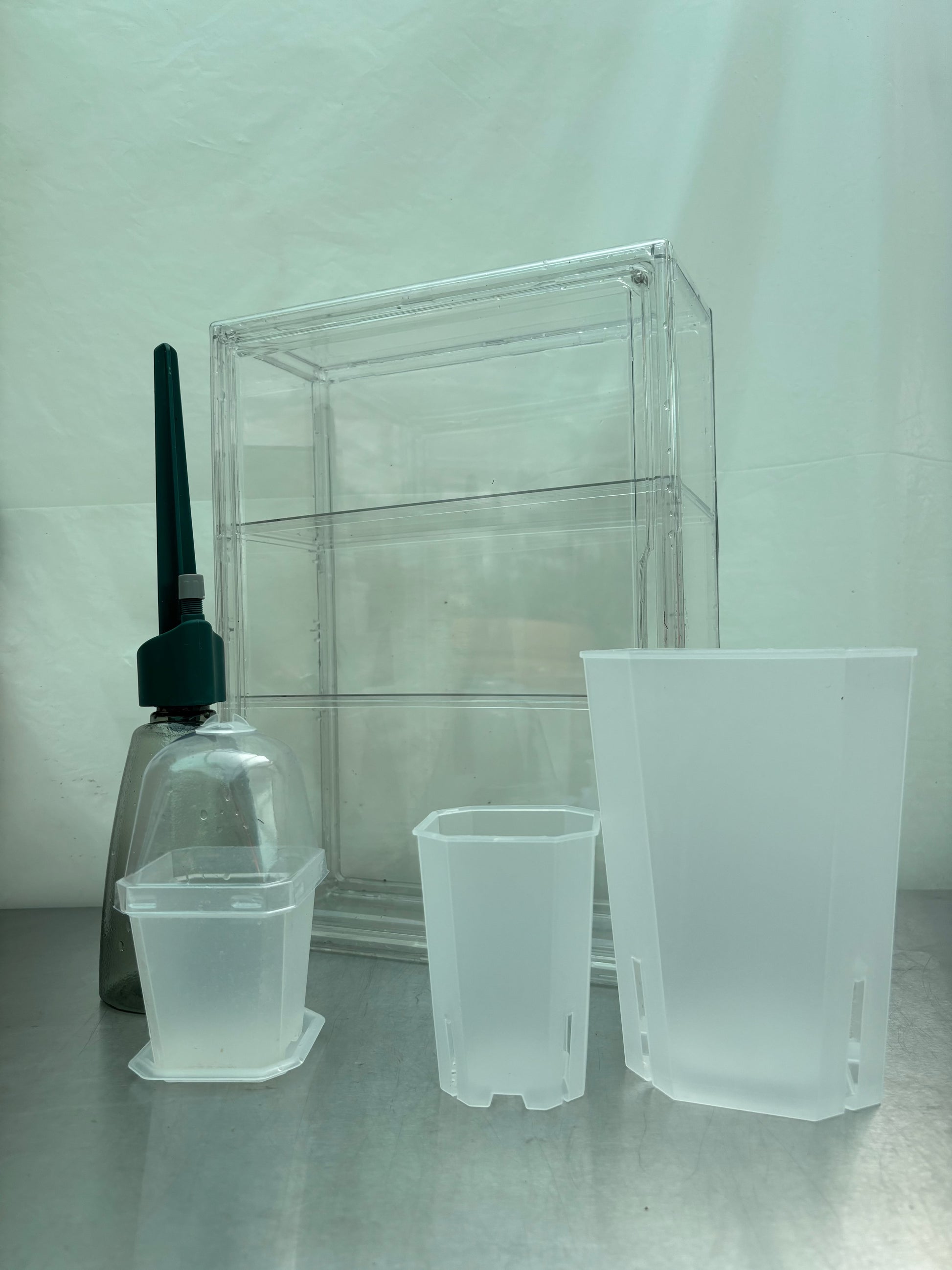 Complete Greenhouse Pro Bundle featuring transparent grow box, watering tool, and various translucent pots for serious plant propagation setups.